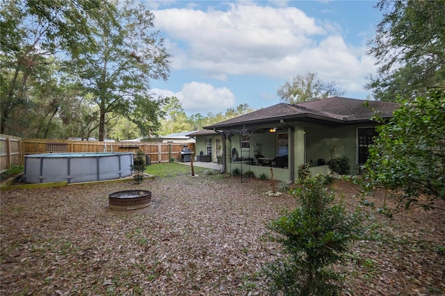 view of yard featuring ceiling fan, a sunroom, and a fenced in pool