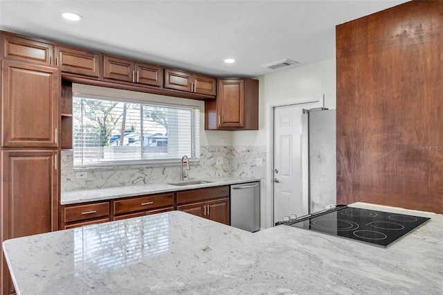 kitchen with appliances with stainless steel finishes, sink, light stone counters, and tasteful backsplash