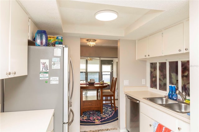 kitchen featuring a raised ceiling, appliances with stainless steel finishes, white cabinetry, and sink