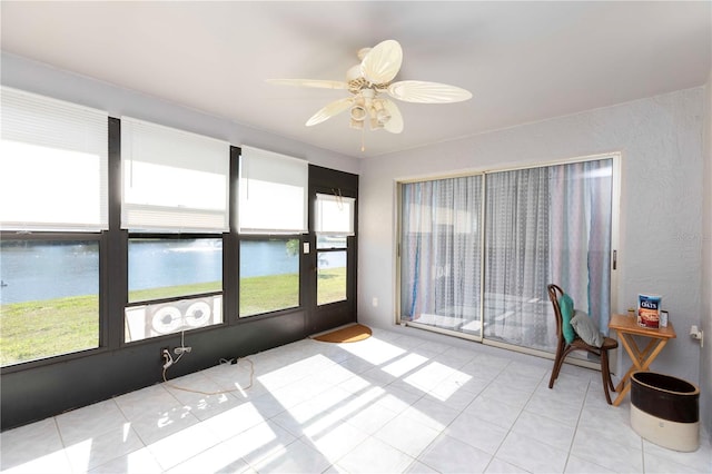 sunroom featuring a water view and ceiling fan