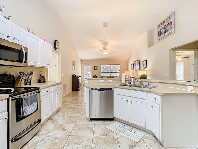 kitchen with appliances with stainless steel finishes, sink, vaulted ceiling, white cabinetry, and ceiling fan