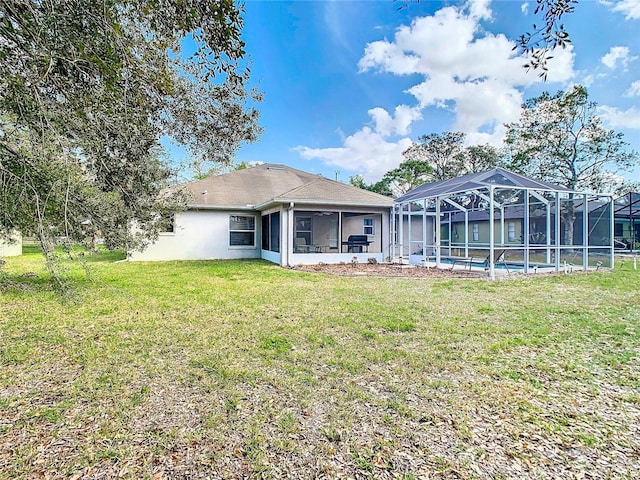 back of house with a yard, glass enclosure, and a sunroom