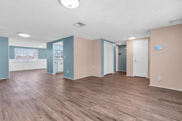 unfurnished living room with a textured ceiling, visible vents, and dark wood-style flooring