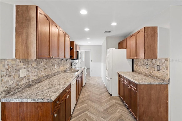 kitchen with white appliances, tasteful backsplash, light stone counters, and light parquet floors