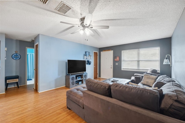 living room featuring hardwood / wood-style floors, ceiling fan, and a textured ceiling