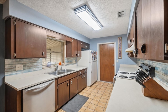 kitchen featuring sink, light tile patterned floors, a textured ceiling, appliances with stainless steel finishes, and decorative backsplash