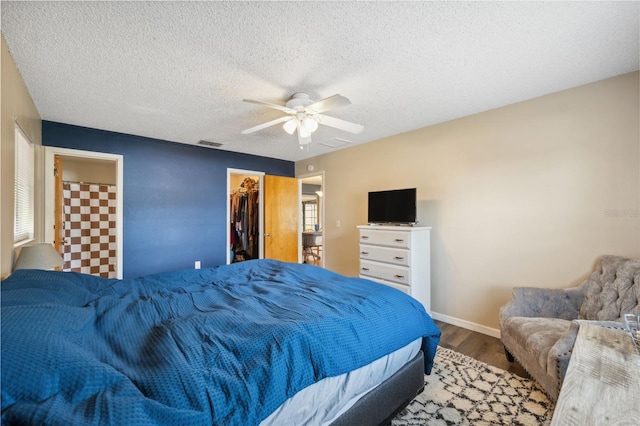 bedroom featuring hardwood / wood-style flooring, a closet, ceiling fan, a textured ceiling, and a spacious closet