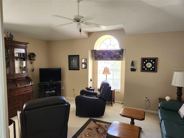 living room featuring baseboards, ceiling fan, and light colored carpet