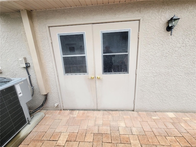 doorway to property with french doors, central AC, and stucco siding