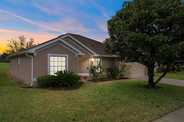 single story home with concrete driveway, a lawn, an attached garage, and stucco siding