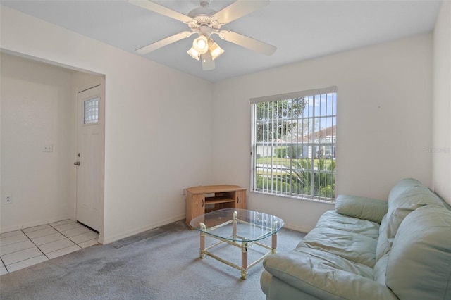 carpeted living room with ceiling fan, baseboards, and tile patterned floors