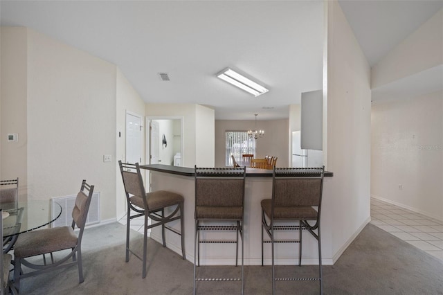 kitchen featuring a breakfast bar, dark countertops, visible vents, and an inviting chandelier