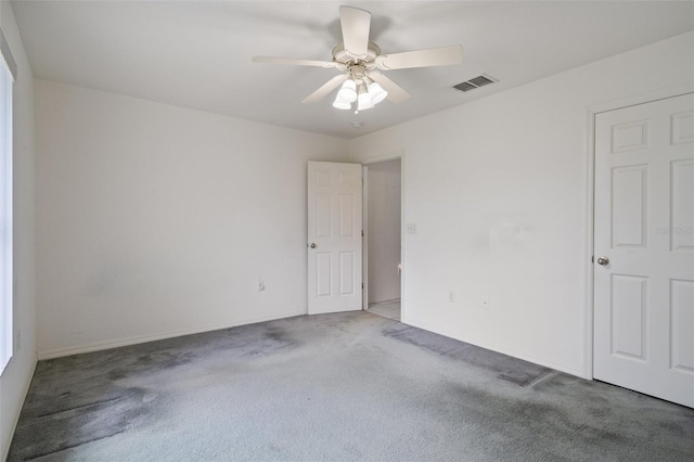 empty room featuring carpet floors, ceiling fan, and visible vents