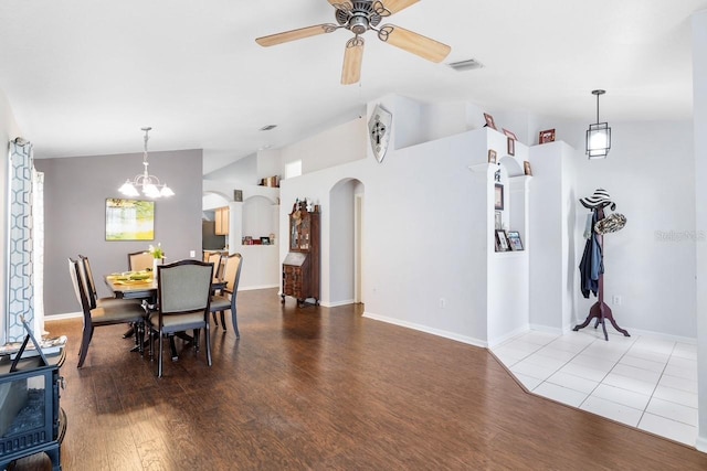 dining space featuring arched walkways, visible vents, light wood-style flooring, vaulted ceiling, and ceiling fan