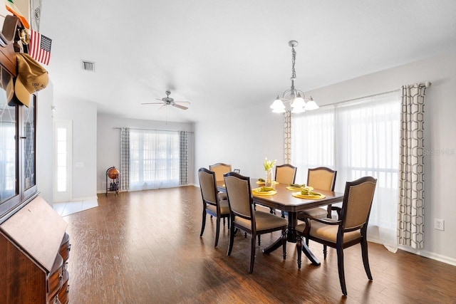 dining space featuring baseboards, visible vents, dark wood finished floors, and ceiling fan with notable chandelier