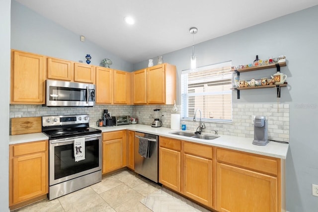 kitchen featuring appliances with stainless steel finishes, hanging light fixtures, vaulted ceiling, light countertops, and a sink