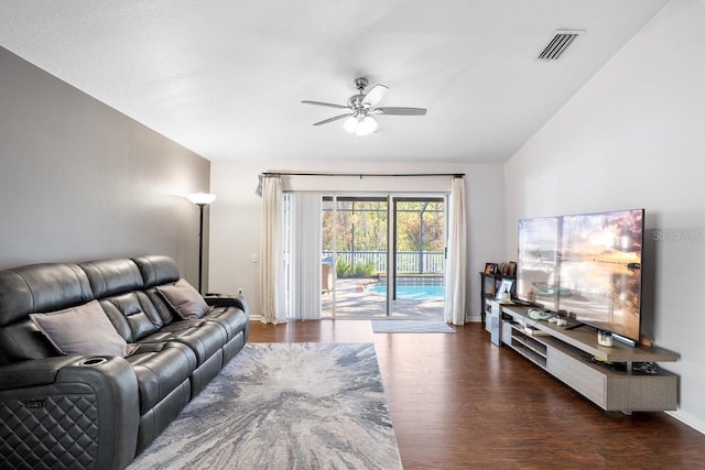 living area featuring baseboards, visible vents, a ceiling fan, dark wood-style floors, and vaulted ceiling