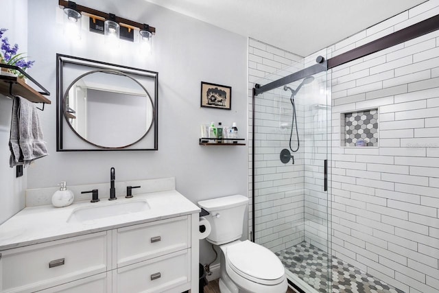 bathroom with toilet, a stall shower, and vanity