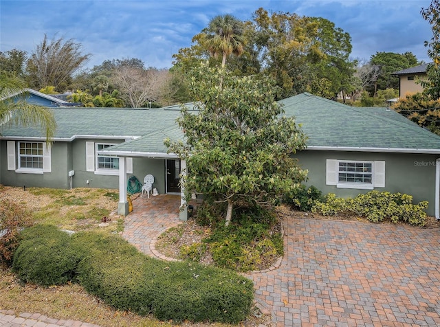 ranch-style house with roof with shingles and stucco siding