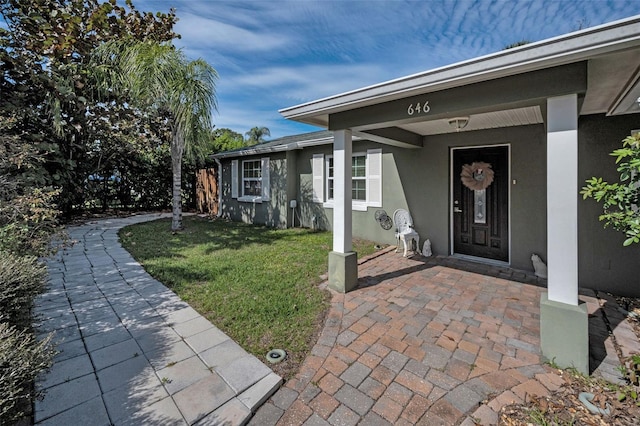 entrance to property featuring a yard and stucco siding