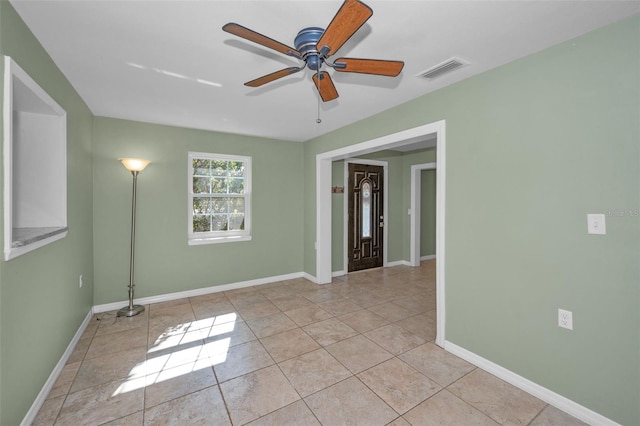 unfurnished room featuring a ceiling fan, tile patterned flooring, visible vents, and baseboards