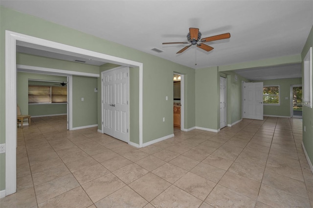 empty room featuring ceiling fan, light tile patterned floors, visible vents, and baseboards