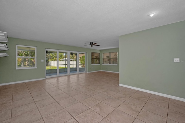 unfurnished room with a ceiling fan, a textured ceiling, baseboards, and light tile patterned floors