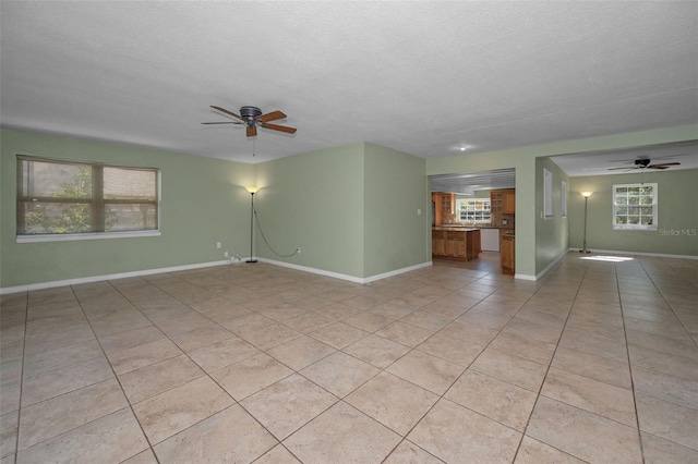 spare room with light tile patterned flooring, ceiling fan, a textured ceiling, and baseboards