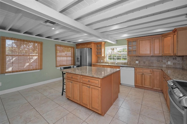 kitchen featuring stainless steel appliances, backsplash, a kitchen island, beamed ceiling, and baseboards