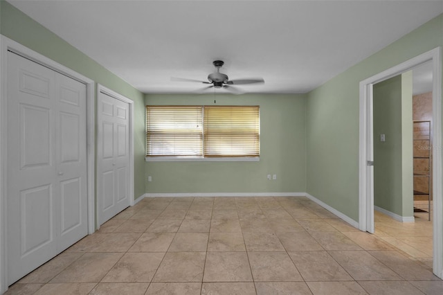 unfurnished bedroom featuring light tile patterned floors, a closet, baseboards, and a ceiling fan