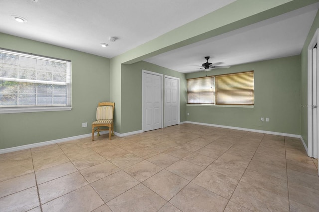 unfurnished bedroom with light tile patterned floors, a closet, a ceiling fan, and baseboards