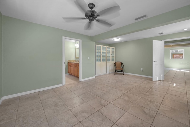 unfurnished room featuring light tile patterned floors, baseboards, visible vents, and a ceiling fan