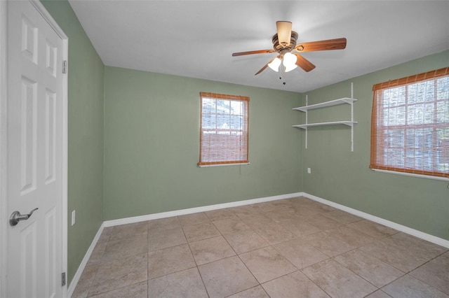 tiled spare room featuring baseboards and a ceiling fan