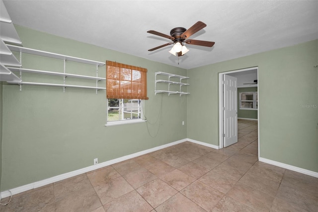 tiled empty room with baseboards and a ceiling fan