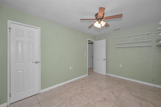 unfurnished room with a ceiling fan, tile patterned flooring, visible vents, and baseboards