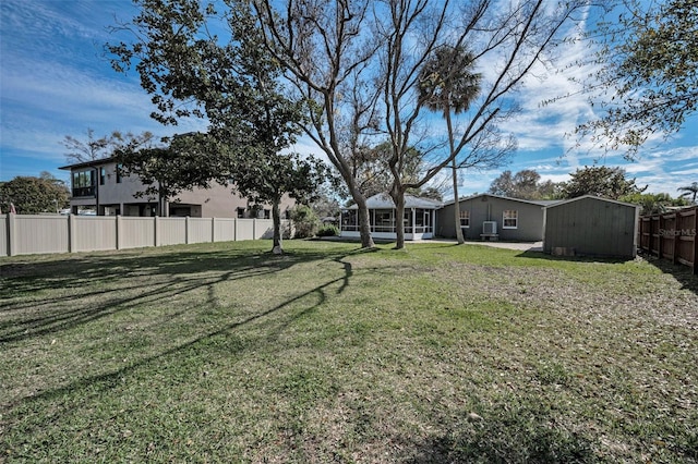 view of yard with a sunroom, fence, an outdoor structure, and a shed