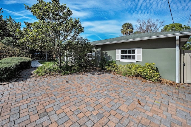 view of front of property featuring a patio area, roof with shingles, and stucco siding