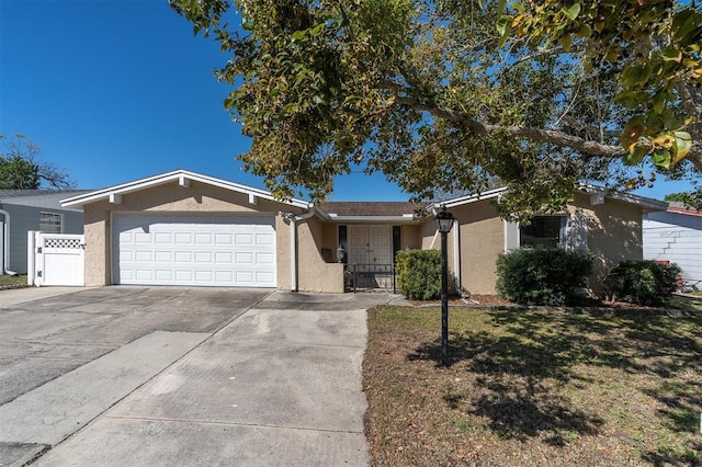 single story home with concrete driveway, an attached garage, fence, and stucco siding