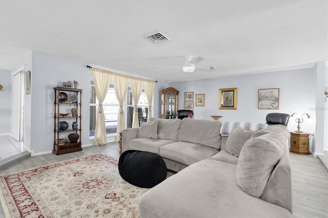 living area with ceiling fan, wood finished floors, visible vents, and baseboards