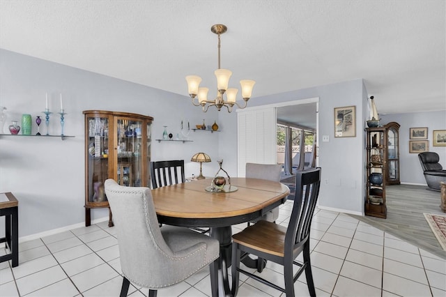 dining space with a textured ceiling, light tile patterned flooring, baseboards, and a notable chandelier