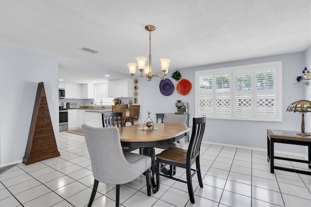 dining area with a chandelier, a textured ceiling, baseboards, and light tile patterned floors