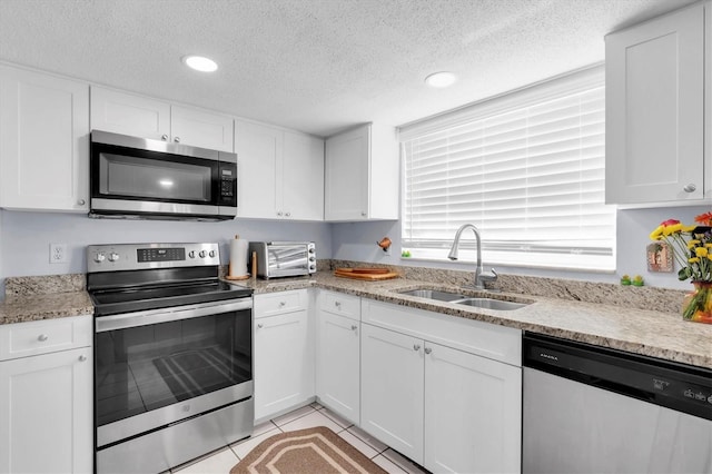 kitchen with appliances with stainless steel finishes, a sink, and white cabinetry