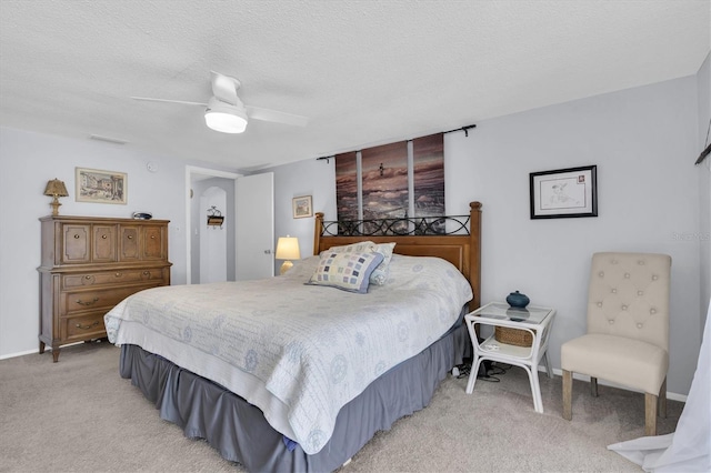 bedroom featuring light carpet, ceiling fan, visible vents, and a textured ceiling