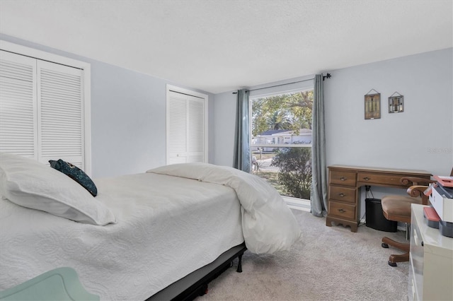 carpeted bedroom featuring a textured ceiling and multiple closets