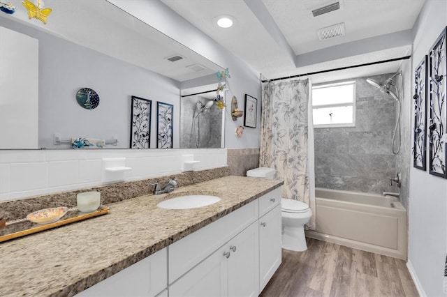 bathroom featuring shower / tub combo with curtain, tile walls, visible vents, toilet, and wood finished floors