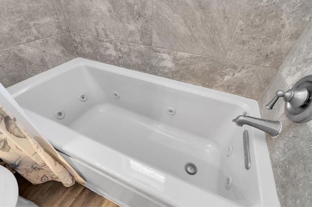 full bathroom with a jetted tub and wood finished floors