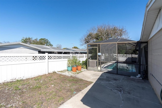 view of yard with a patio area, a fenced backyard, and a lanai