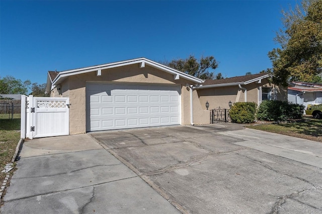 single story home with a garage, fence, driveway, a gate, and stucco siding