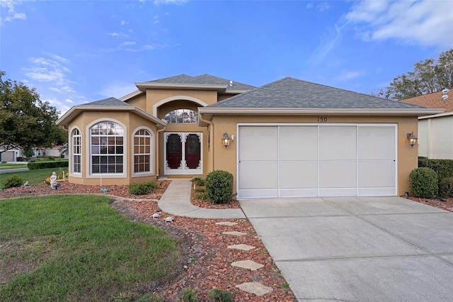 ranch-style house with driveway, a garage, a front lawn, roof with shingles, and stucco siding