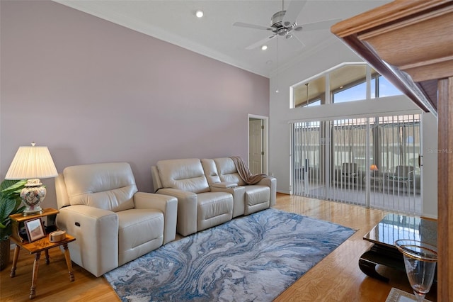 living room featuring a high ceiling, ornamental molding, wood finished floors, and a ceiling fan